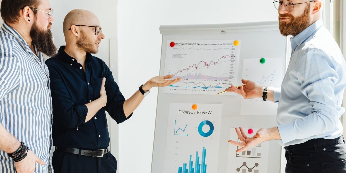 A team collaborates, discussing recent market trends and potential drivers on a whiteboard.