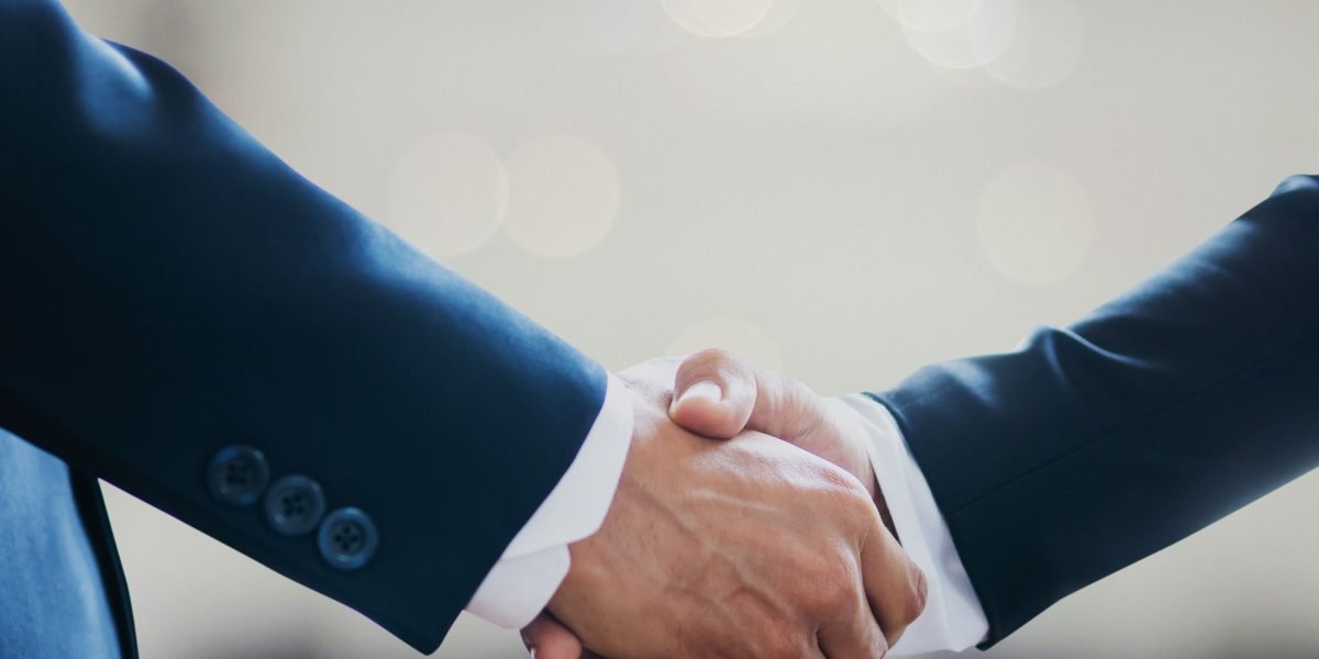 Business professionals shaking hands across a table, symbolizing successful partnerships and strategic alliances in the competitive AI market.