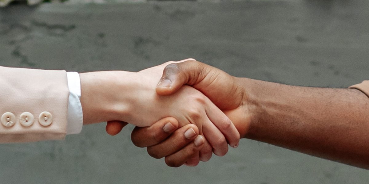 Two business professionals shaking hands firmly after a successful negotiation, symbolizing a merger or acquisition deal.
